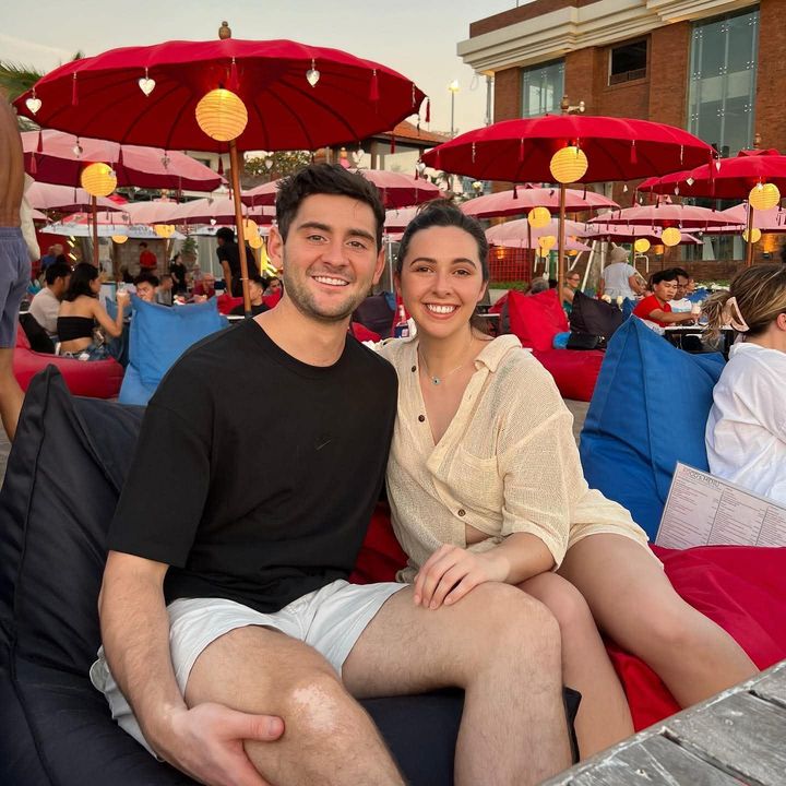 Hayden and Phoebe on bean bags under red umbrellas at sunset